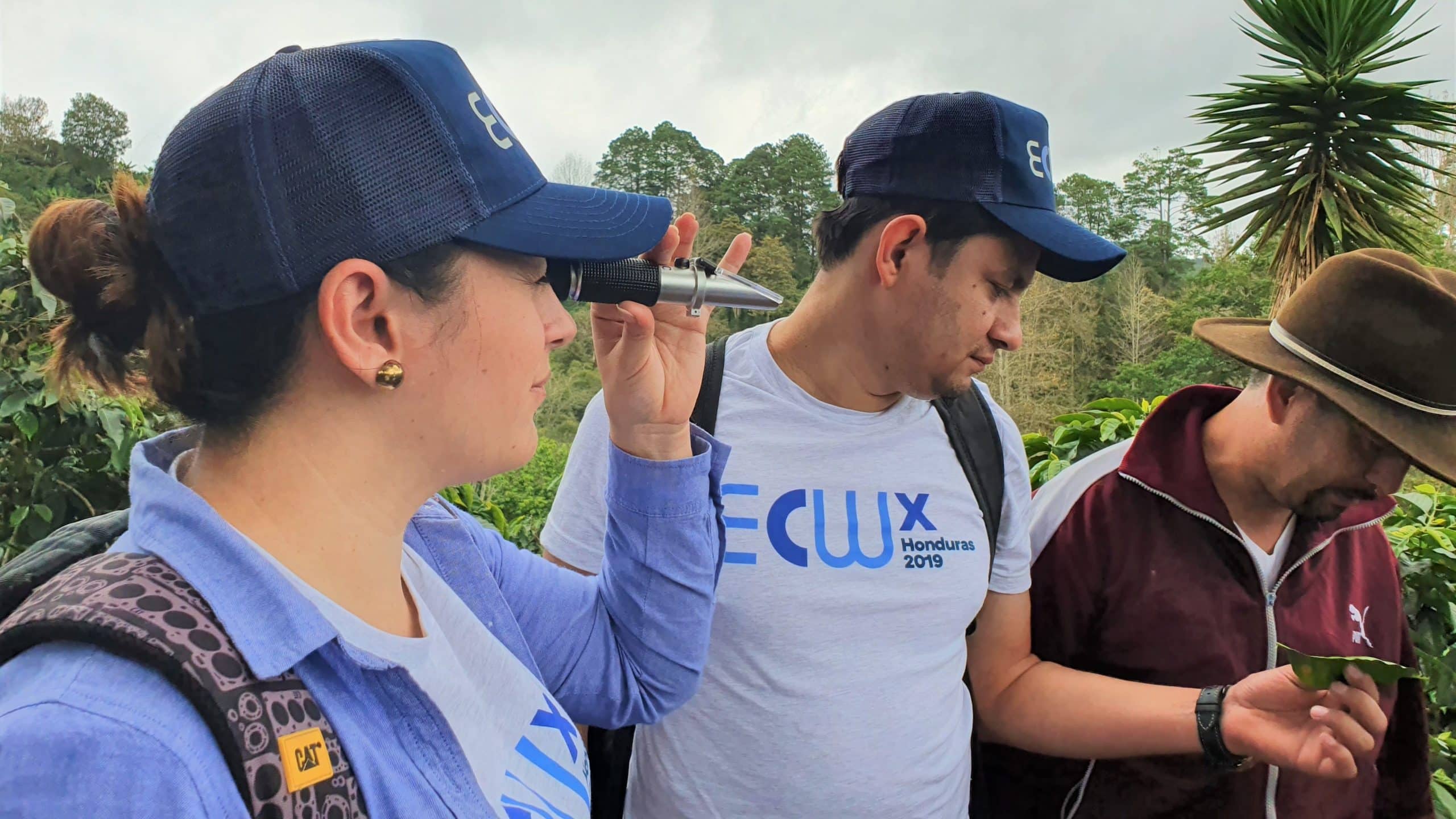 A participant looks through her refractometer so test cherry ripeness while another participant looks at a diseased coffee leaf.