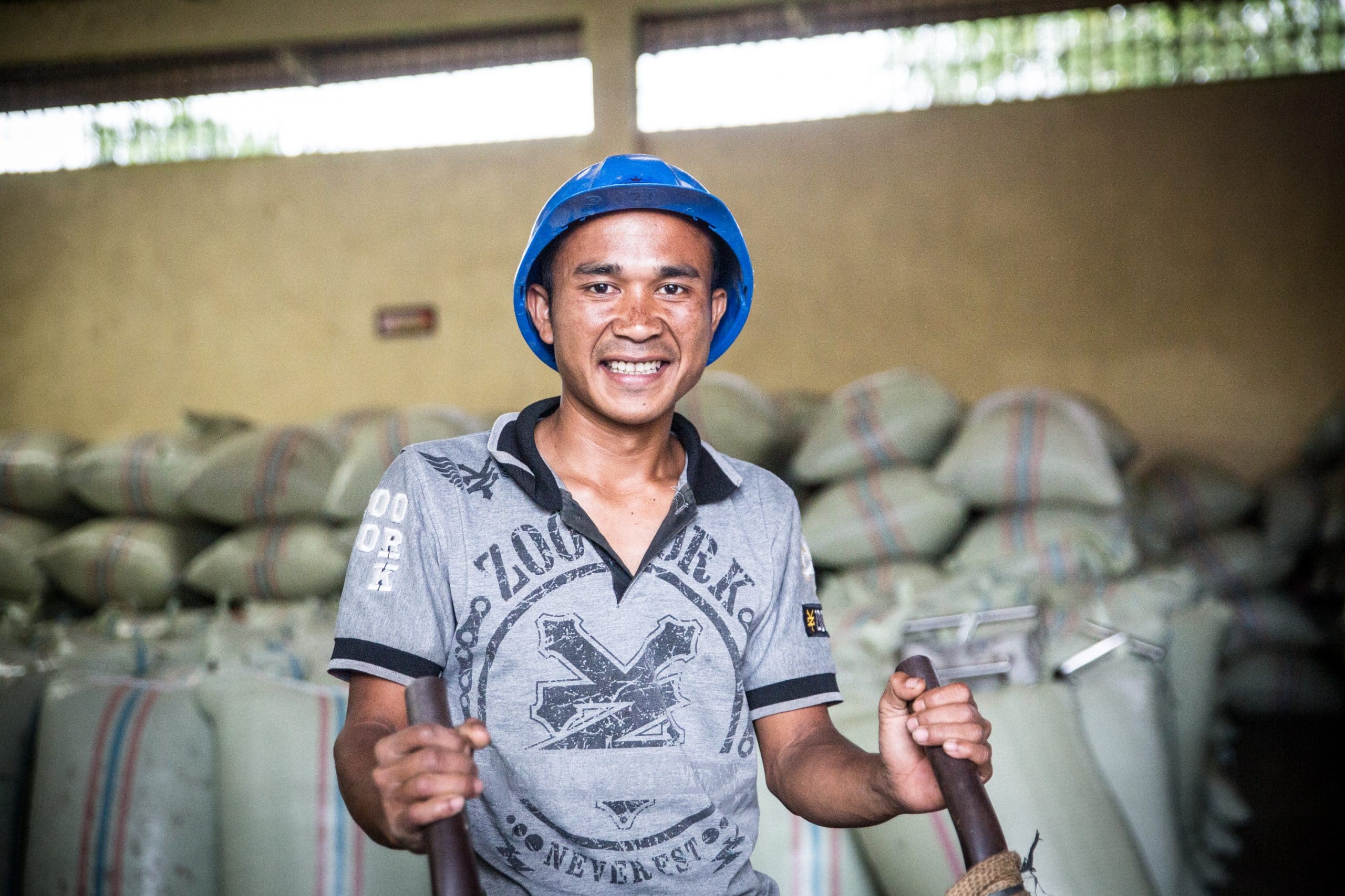 Juliman, a worker at the Kopepi Ketiara Cooperative, the bagged whole dried coffee in the warehouse.
 (Photo: Blake Dunlop)